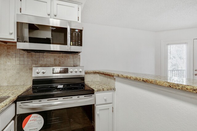 kitchen featuring stainless steel appliances, light stone countertops, white cabinetry, and tasteful backsplash