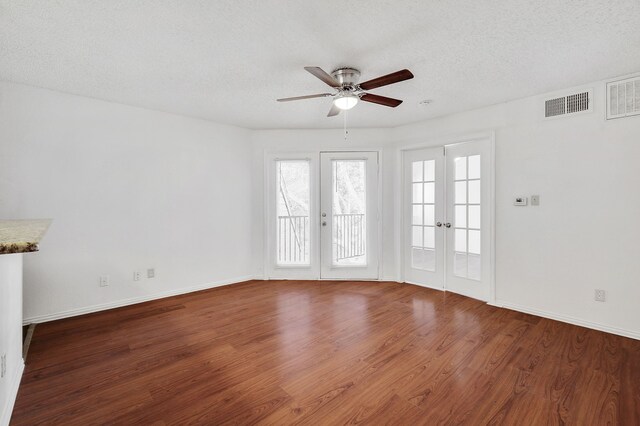 unfurnished room with a textured ceiling, french doors, a ceiling fan, wood finished floors, and visible vents