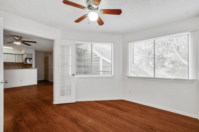 unfurnished room featuring ceiling fan, a textured ceiling, french doors, baseboards, and dark wood-style floors