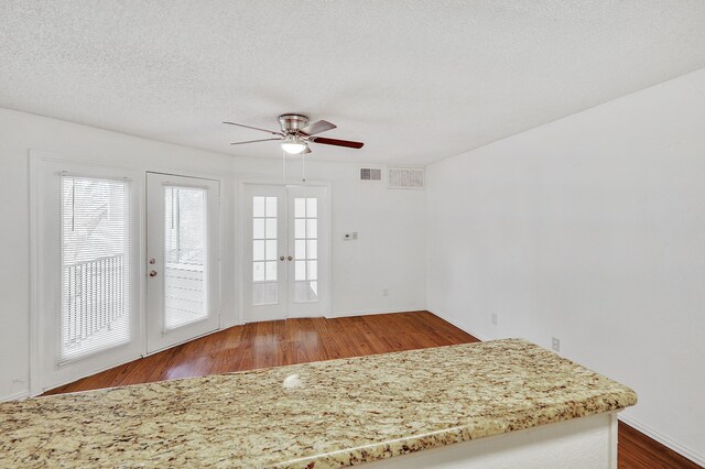 interior space with french doors, a ceiling fan, visible vents, wood finished floors, and baseboards