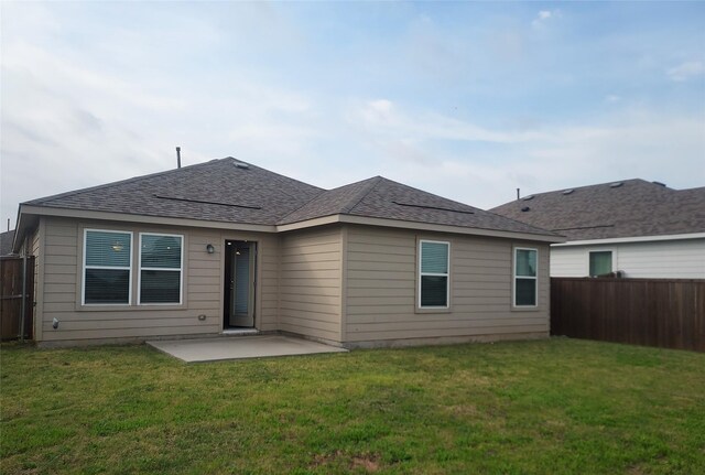 back of house featuring fence, a yard, a patio area, and roof with shingles