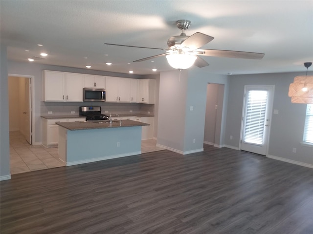 kitchen with appliances with stainless steel finishes, ceiling fan, white cabinets, and open floor plan