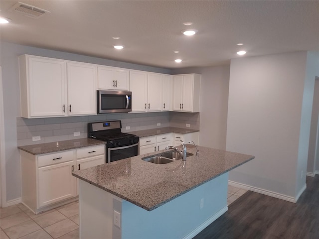 kitchen with a sink, stone counters, and appliances with stainless steel finishes