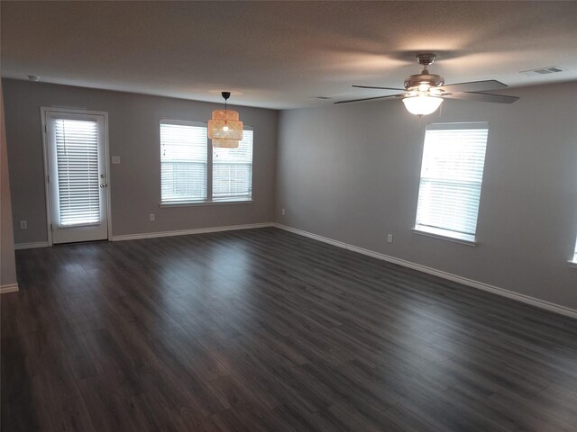unfurnished room with dark wood-style flooring, ceiling fan, visible vents, and baseboards