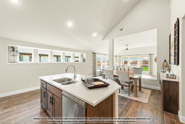 kitchen featuring a sink, light countertops, stainless steel dishwasher, and wood finished floors