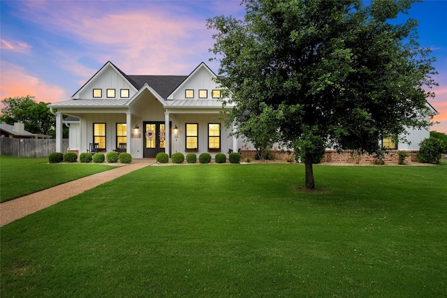 view of front facade featuring a front lawn, fence, french doors, a standing seam roof, and board and batten siding