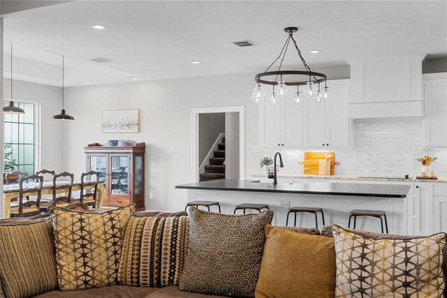 interior space featuring hanging light fixtures, decorative backsplash, white cabinetry, and visible vents