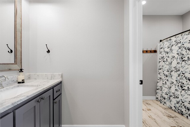full bath with baseboards, curtained shower, wood finished floors, and vanity