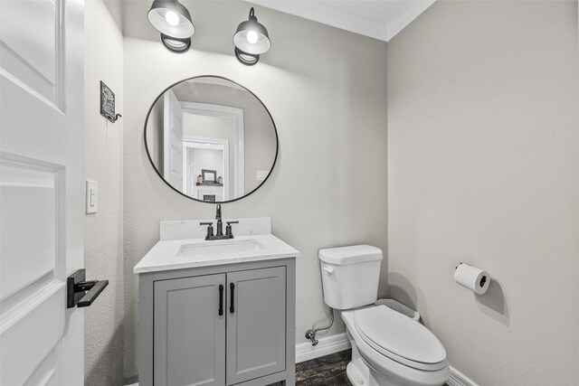 half bathroom featuring crown molding, toilet, baseboards, and vanity
