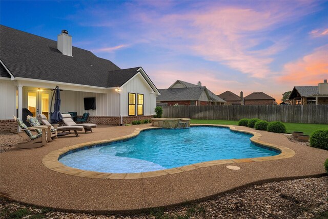 pool at dusk featuring a pool with connected hot tub, a fenced backyard, and a patio area