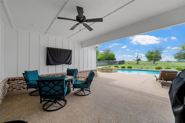 view of patio / terrace with a fire pit, a pool with connected hot tub, fence, and a ceiling fan