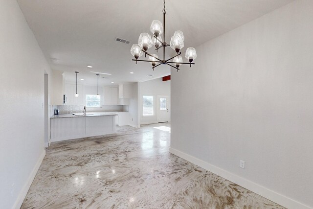 unfurnished dining area featuring a sink, a chandelier, baseboards, vaulted ceiling, and visible vents