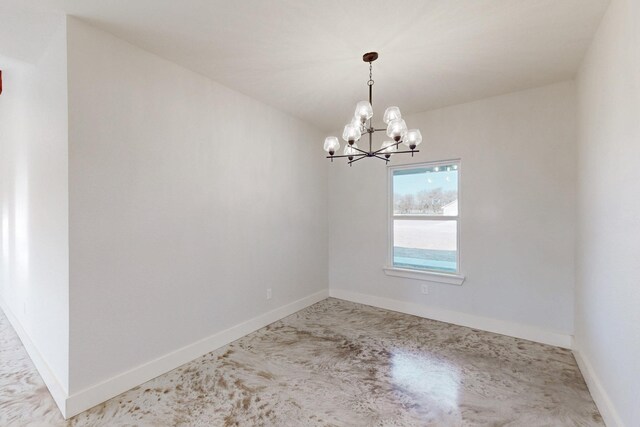 spare room featuring baseboards and a chandelier