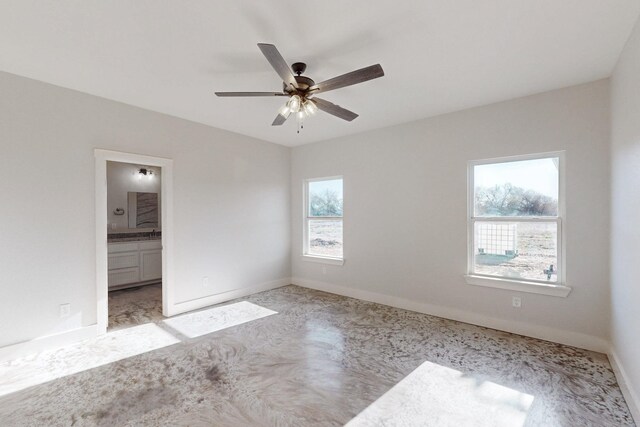 unfurnished bedroom with connected bathroom, a ceiling fan, and baseboards