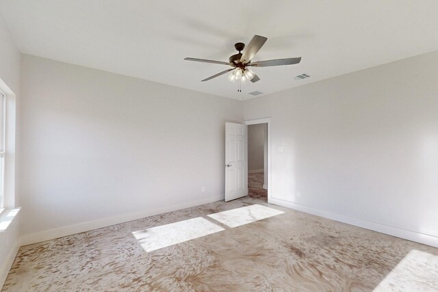 empty room with baseboards, a ceiling fan, and visible vents