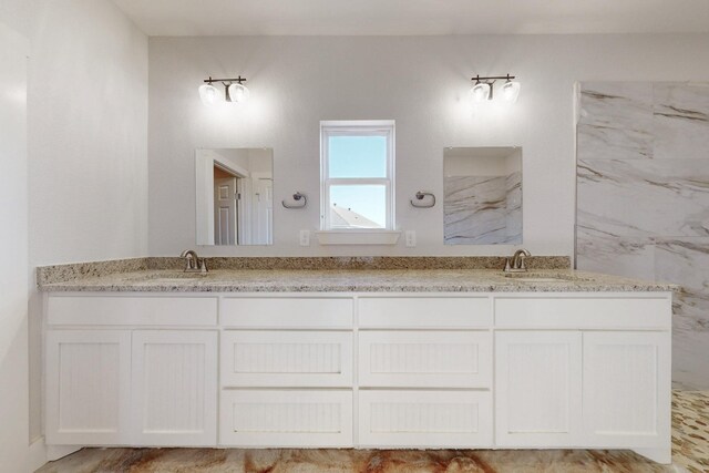 bathroom featuring double vanity, a sink, and a marble finish shower