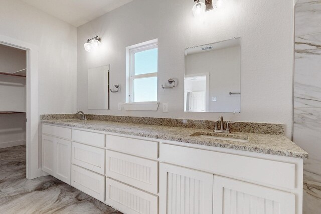 full bath featuring double vanity, a spacious closet, a sink, and visible vents