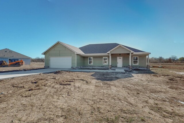 ranch-style home with an attached garage, covered porch, and concrete driveway
