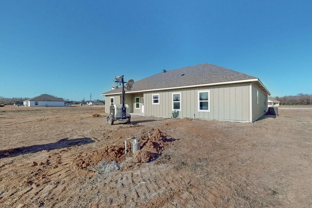 back of house featuring board and batten siding and a shingled roof