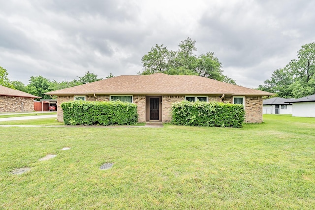 ranch-style house featuring brick siding, a shingled roof, and a front yard