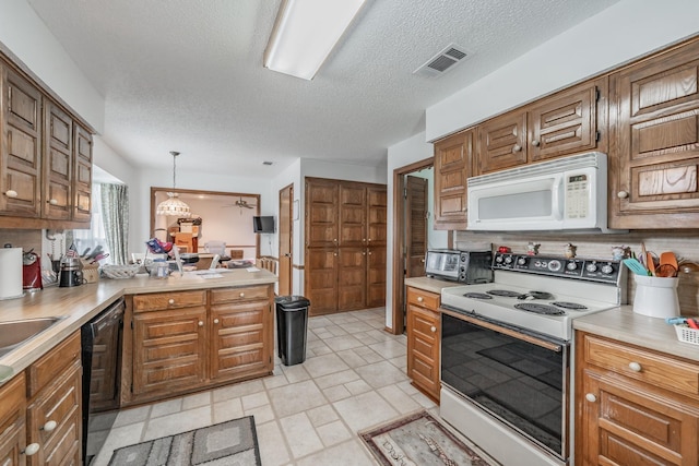 kitchen with a textured ceiling, light countertops, a toaster, a peninsula, and white appliances