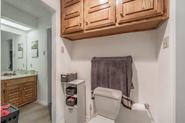 bathroom featuring toilet, baseboards, and vanity