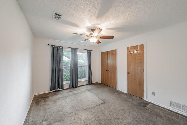 unfurnished bedroom featuring carpet, a textured ceiling, and visible vents