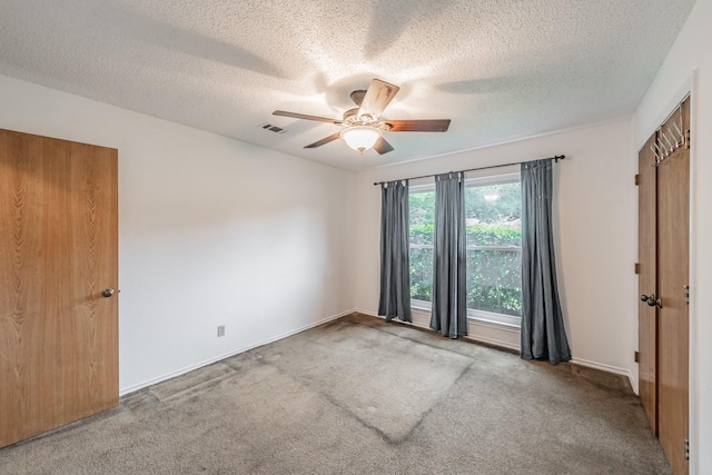 unfurnished bedroom featuring visible vents, a ceiling fan, baseboards, a textured ceiling, and carpet flooring