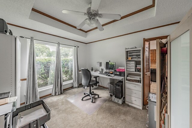 carpeted home office featuring a textured ceiling, a raised ceiling, ceiling fan, and ornamental molding