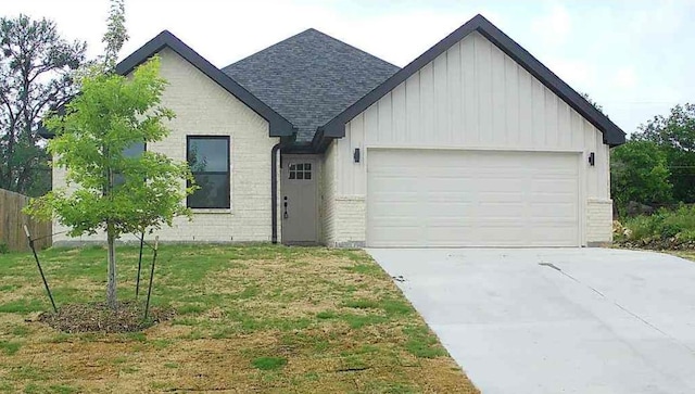 view of front of home featuring roof with shingles, brick siding, board and batten siding, an attached garage, and driveway