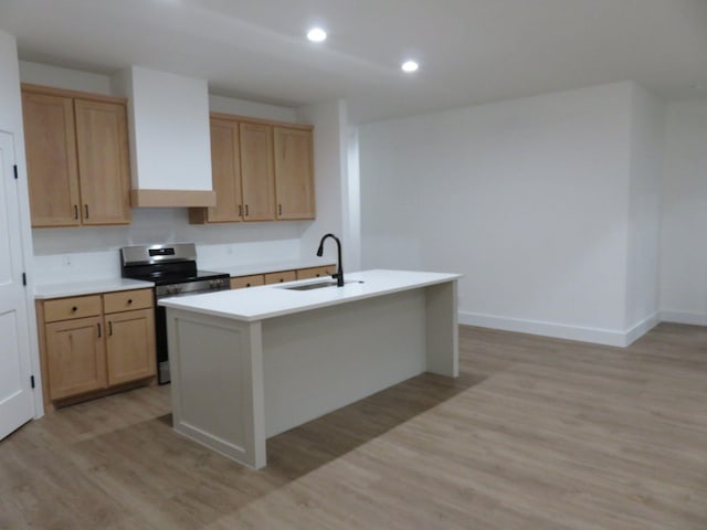 kitchen featuring light brown cabinetry, stainless steel range with electric cooktop, a sink, light countertops, and light wood-style flooring