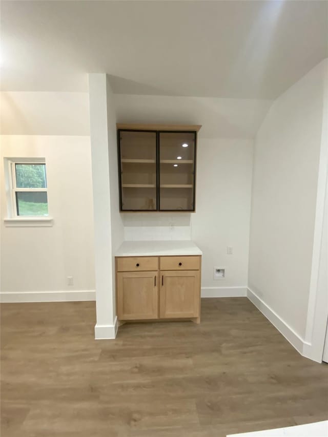 interior space with baseboards, light wood-style flooring, and vaulted ceiling