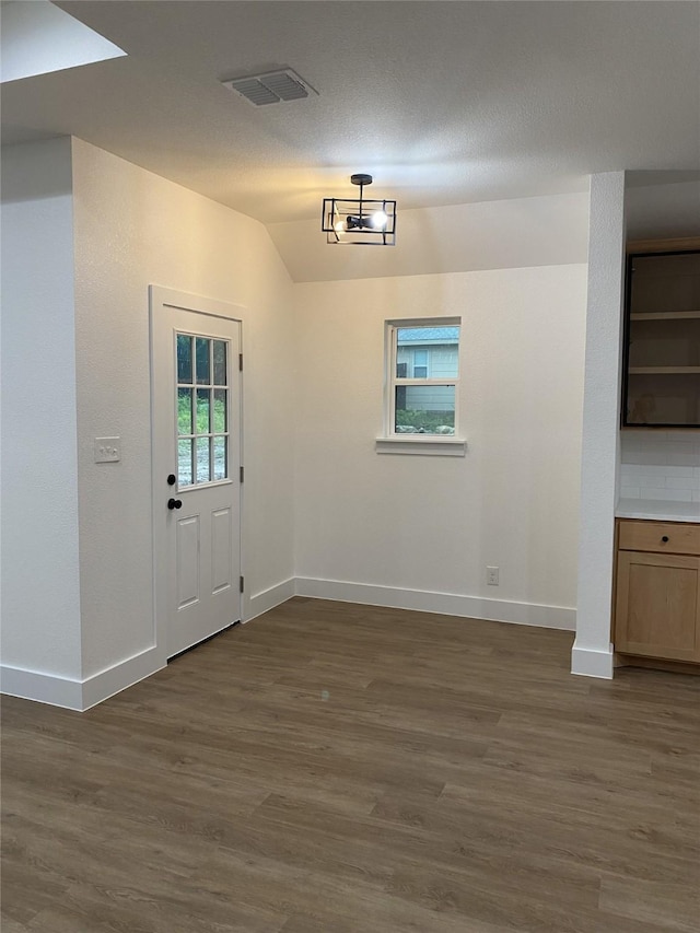 unfurnished dining area featuring vaulted ceiling, baseboards, dark wood-type flooring, and visible vents