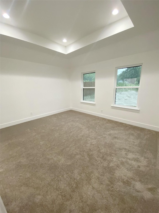 unfurnished room with recessed lighting, baseboards, a tray ceiling, and dark carpet