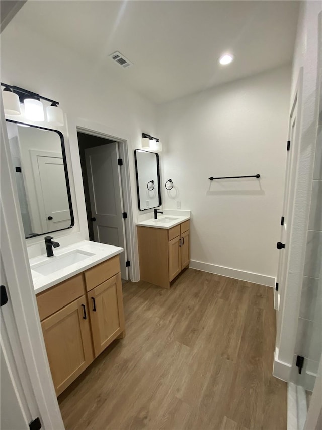 bathroom featuring visible vents, two vanities, a sink, and wood finished floors