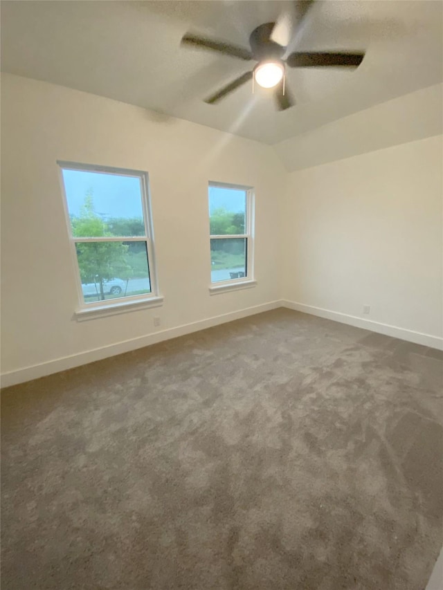 unfurnished room with baseboards, a ceiling fan, dark carpet, and lofted ceiling