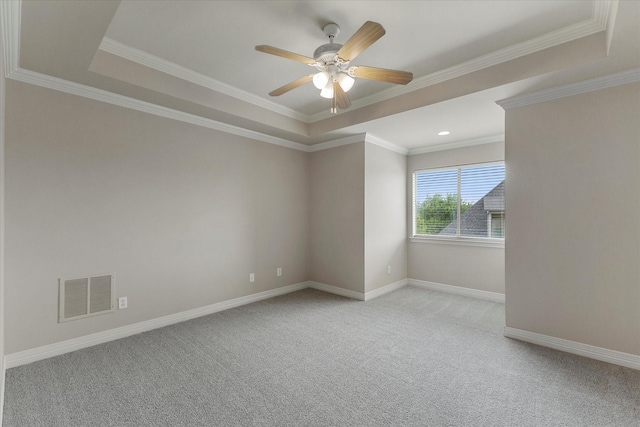 unfurnished room with ceiling fan, light colored carpet, visible vents, a raised ceiling, and baseboards