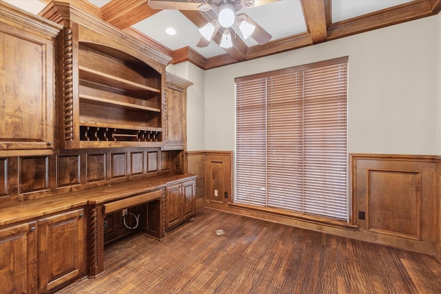 unfurnished office featuring beamed ceiling, a wainscoted wall, coffered ceiling, a ceiling fan, and dark wood finished floors