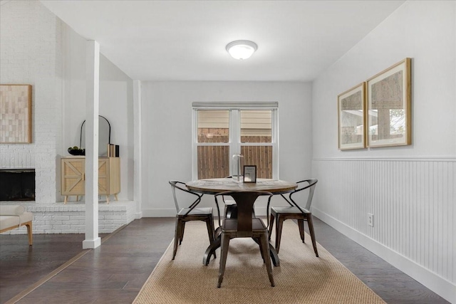 dining area featuring wainscoting, wood finished floors, and a fireplace