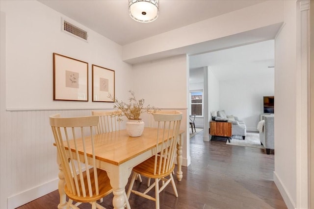 dining room featuring baseboards, wainscoting, wood finished floors, and visible vents
