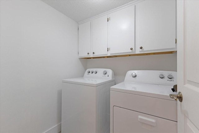 laundry area with a textured ceiling, independent washer and dryer, and cabinet space