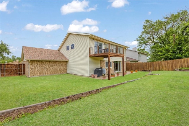 rear view of house featuring a lawn, a balcony, and a fenced backyard