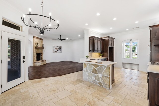 kitchen featuring dark brown cabinetry, light countertops, open floor plan, ornamental molding, and recessed lighting