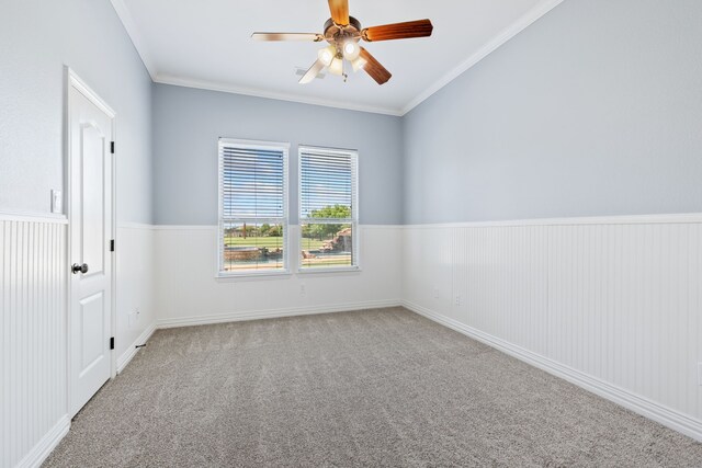 unfurnished room featuring ornamental molding, carpet, ceiling fan, and a wainscoted wall