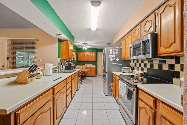 2609 Kimberly Dr, Garland, TX 75040 - kitchen with ceiling fan, light countertops, tasteful backsplash, a sink, and appliances with stainless steel finishes