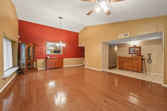 2609 Kimberly Dr, Garland, TX 75040 - unfurnished living room featuring baseboards, ceiling fan with notable chandelier, wood finished floors, and high vaulted ceiling
