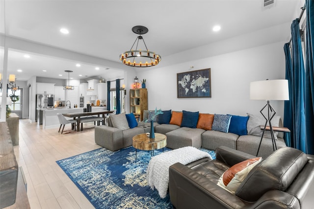 living room with light wood-style floors, visible vents, recessed lighting, and a notable chandelier