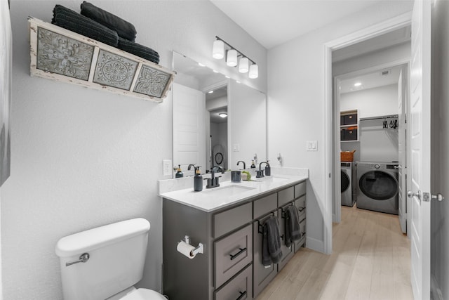 full bathroom featuring double vanity, washing machine and clothes dryer, wood finished floors, a sink, and toilet