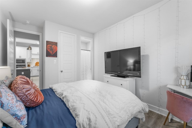 bedroom featuring baseboards, wood finished floors, and ensuite bath