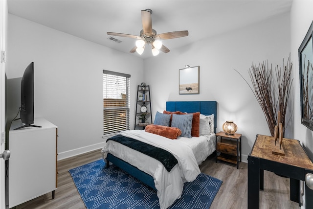 bedroom featuring baseboards, ceiling fan, wood finished floors, and visible vents